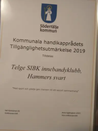 Kommunstyrelsens ordförande Boel Godner delar ut tillgänglighetsutmärkelsen till Telge SIBK, Hammers svart. Mi Karlung, tränare och lagledare, Simon Sallander, spelare, Kristina Sallander