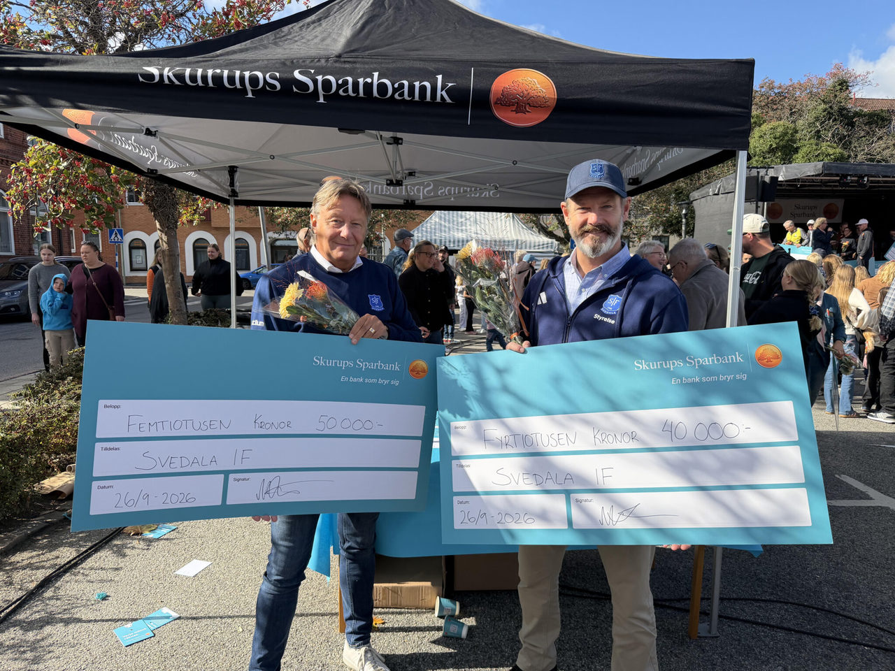 Ulf Mohlin Fagerström och Johan Pagels tog tacksamt emot symboliska checkar på torget i Skurup