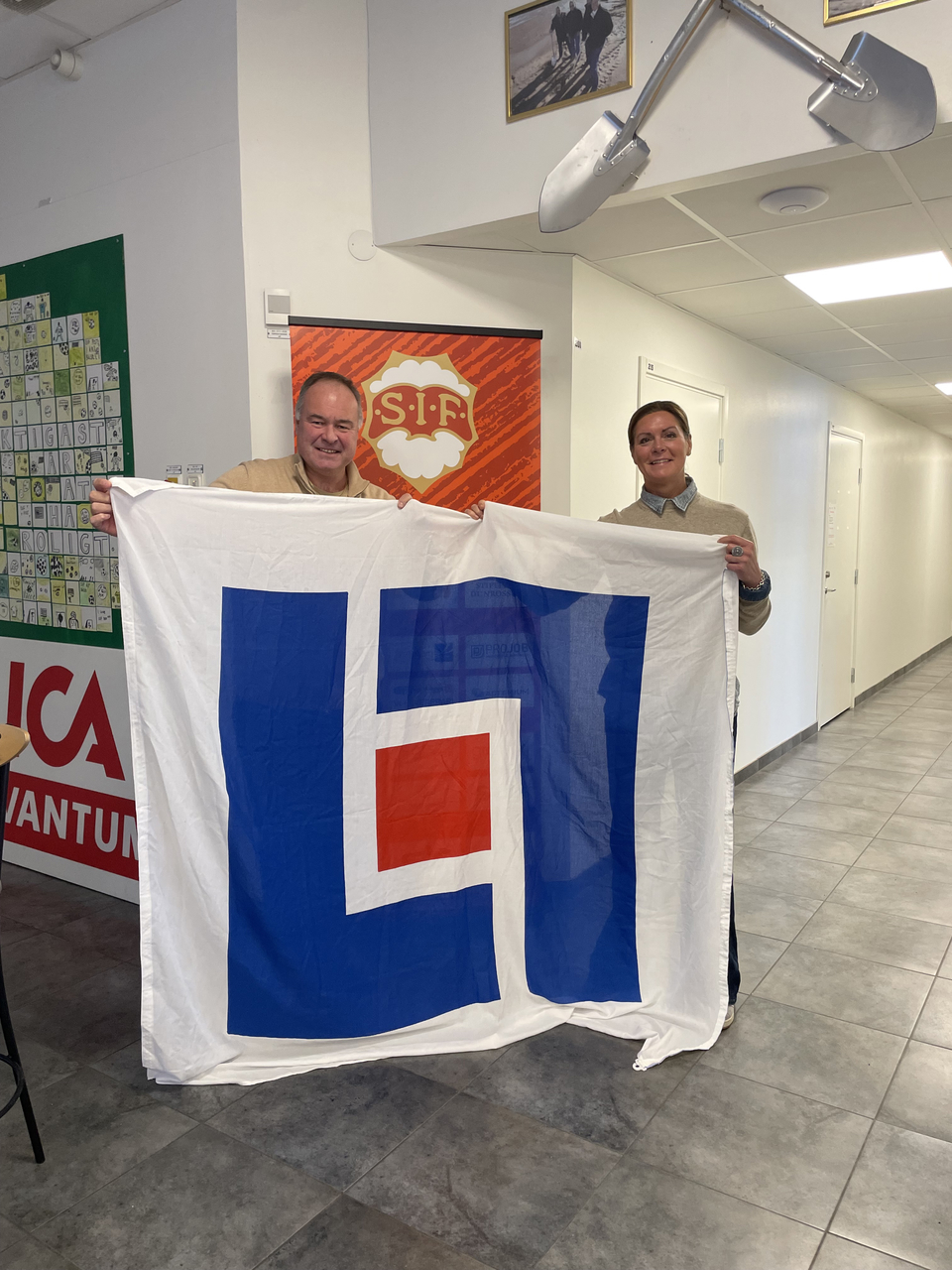 Pontus Roos och Louise Karlsson poserar tillsammans med Länsförsäkringars flagga!