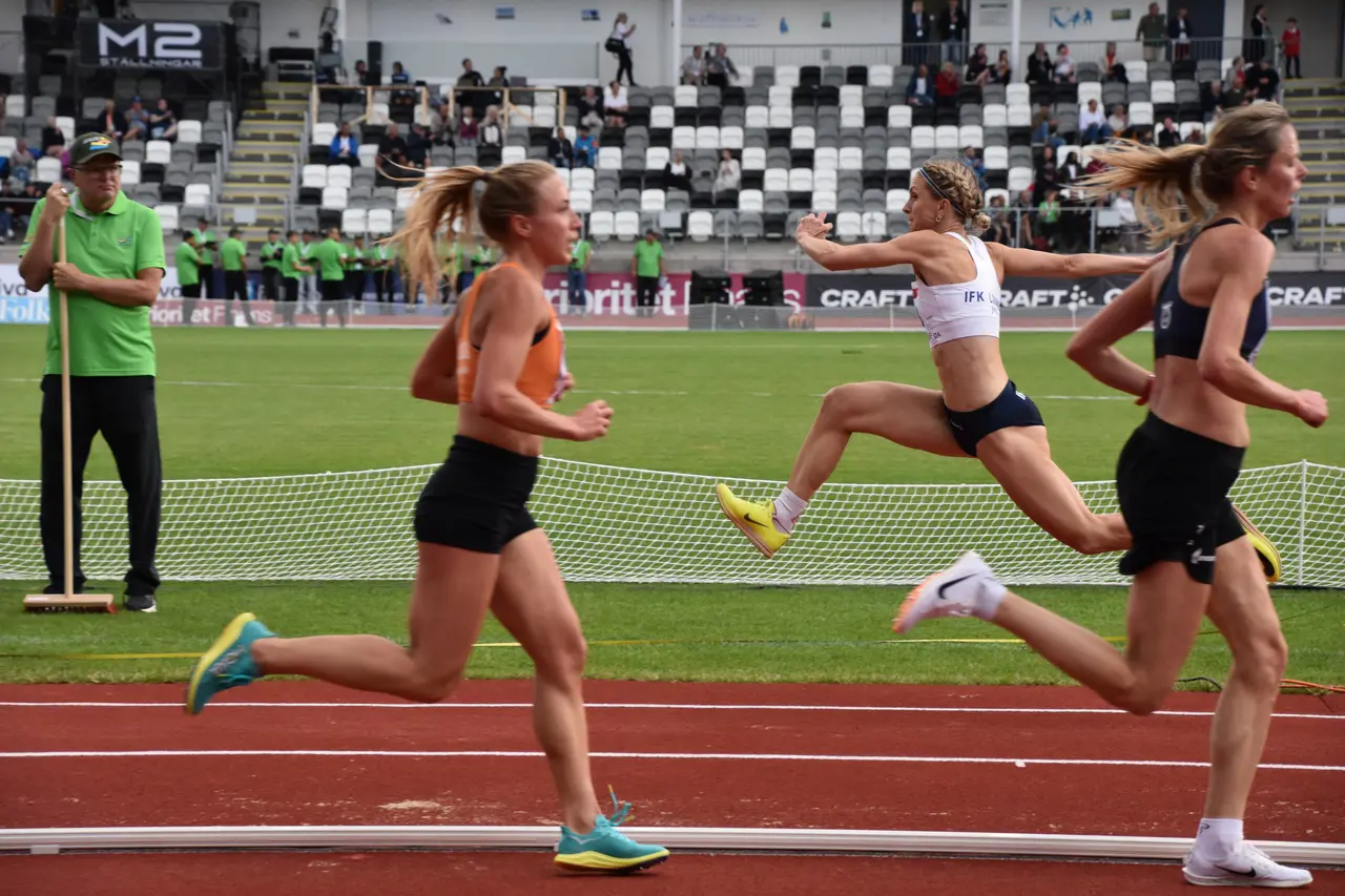 Malin ”mötte” tiotusenmeterslöparna när hon hoppade i de sista omgångarna i trestegsfinalen. 13.02 räckte till en fjärdeplats. Foto: Janne Åkerblom
