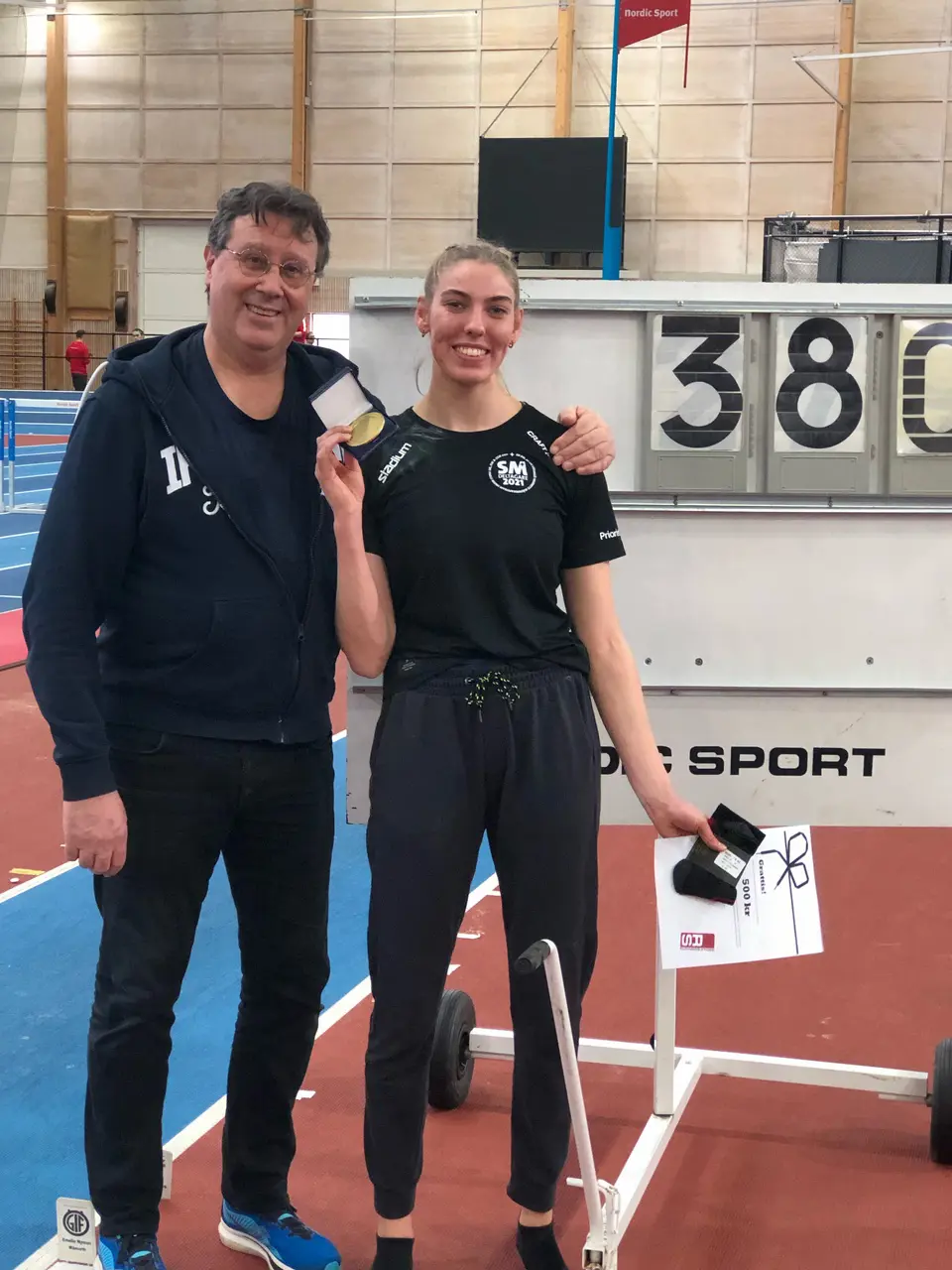 Johanna Hellan tillsammans med coach Robert Eliasson framför resultatskylten med de tre siffrorna 3, 8 och 0.